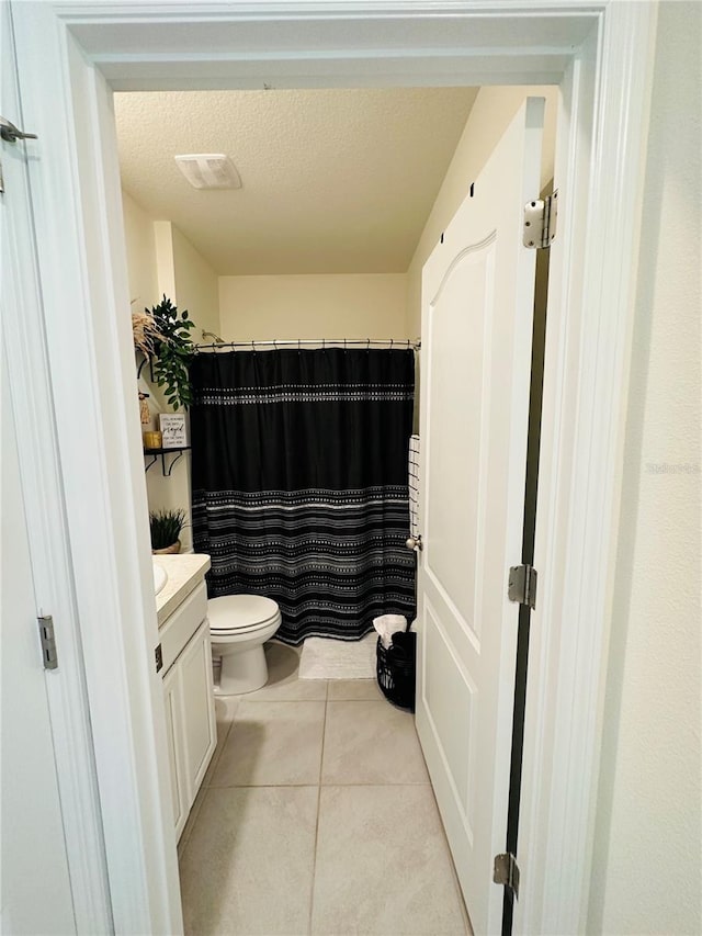 bathroom with a textured ceiling, vanity, tile floors, and toilet