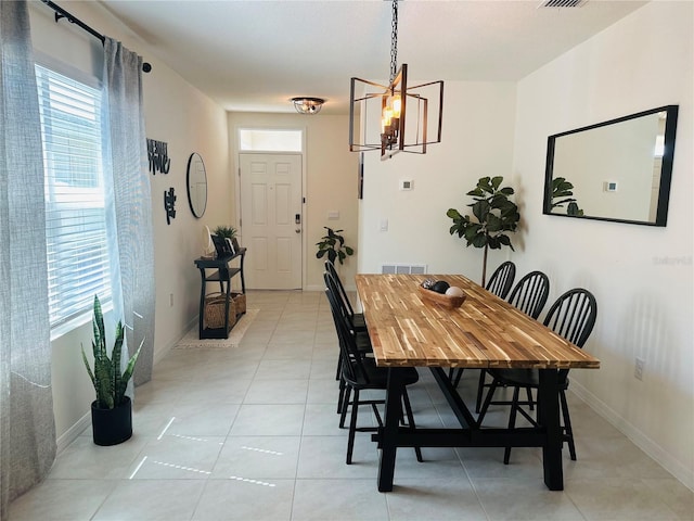 tiled dining space with plenty of natural light and a notable chandelier