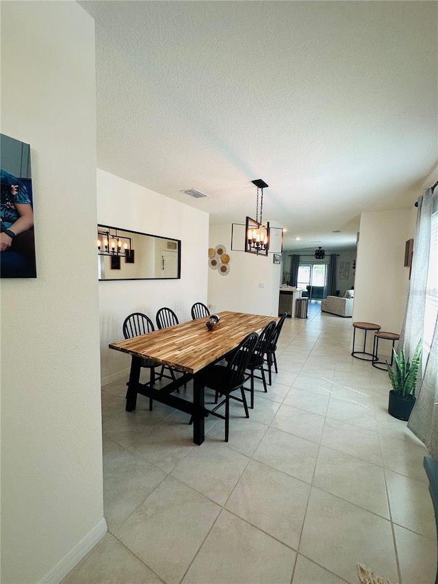 tiled dining area with a chandelier and a textured ceiling