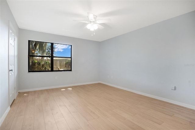 empty room with ceiling fan, light wood-type flooring, and baseboards