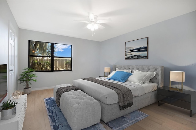 bedroom with light wood-type flooring, ceiling fan, and baseboards