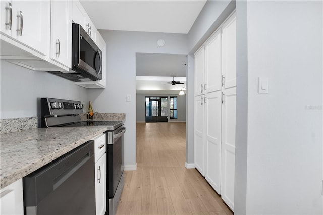 kitchen with light stone counters, stainless steel appliances, light wood-style flooring, white cabinetry, and baseboards