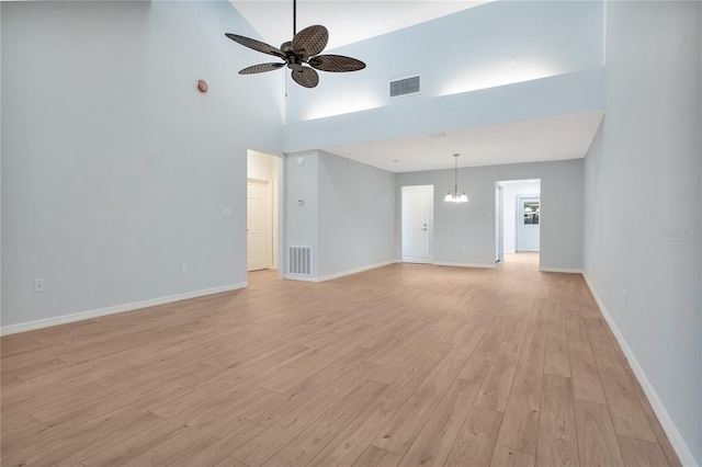 unfurnished living room featuring ceiling fan with notable chandelier, baseboards, visible vents, and light wood-style floors