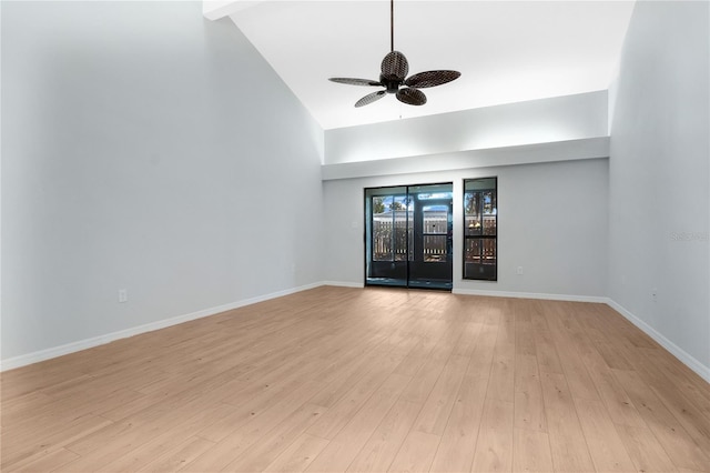 empty room featuring a ceiling fan, high vaulted ceiling, light wood-style flooring, and baseboards