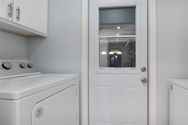 clothes washing area featuring cabinet space and separate washer and dryer