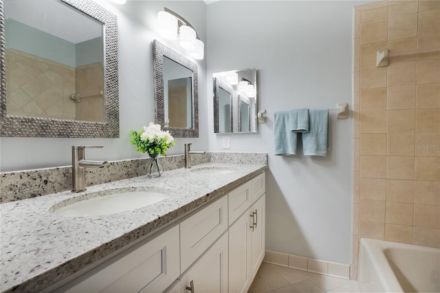 full bath featuring baseboards, double vanity, a sink, and tile patterned floors