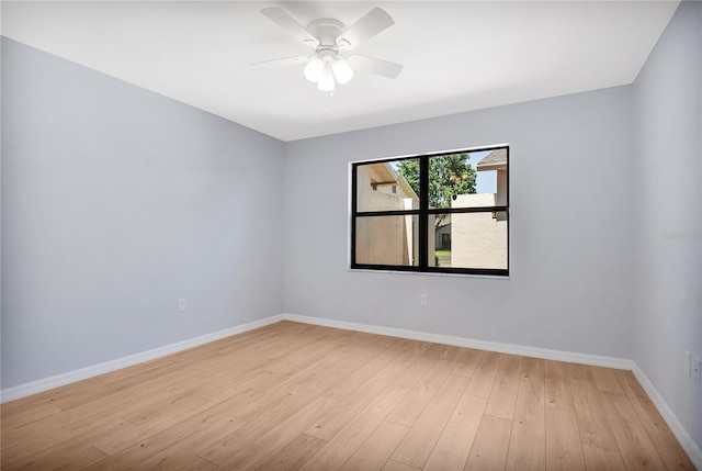 empty room featuring light wood finished floors, a ceiling fan, and baseboards