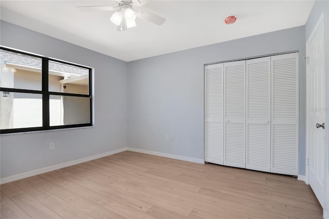 unfurnished bedroom featuring light wood finished floors, a closet, a ceiling fan, and baseboards