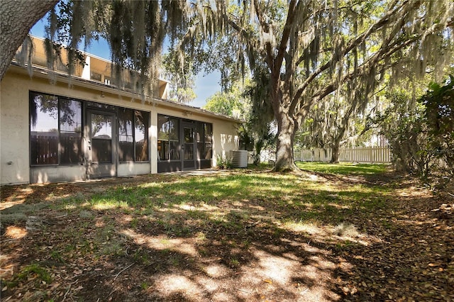 view of yard with central AC unit, a sunroom, and fence