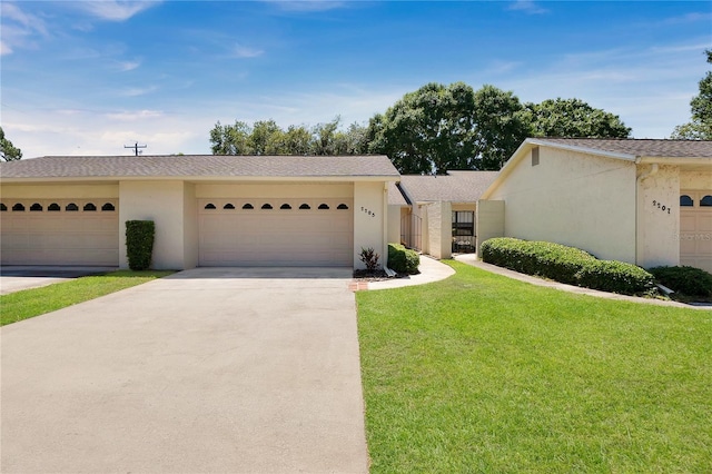 view of front of house featuring an attached garage, driveway, a front lawn, and stucco siding