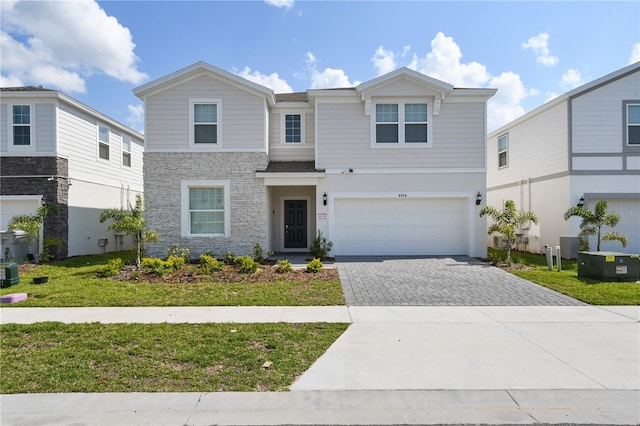 view of front of property featuring central air condition unit, a garage, and a front yard