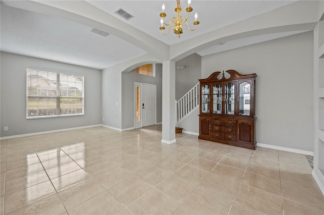 foyer entrance with a textured ceiling, an inviting chandelier, and light tile floors