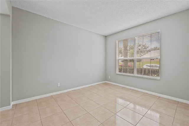 spare room featuring a textured ceiling and light tile flooring