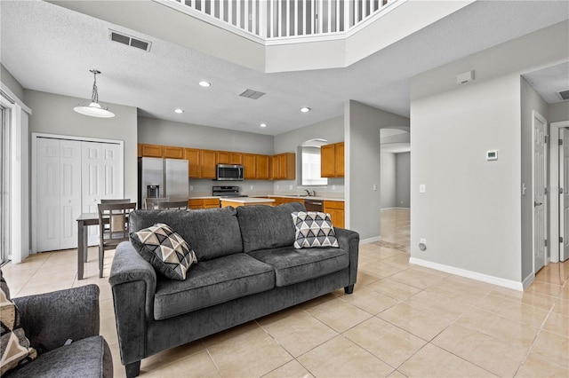 living room featuring sink, a textured ceiling, and light tile floors