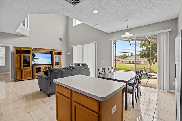 kitchen featuring decorative light fixtures, light tile flooring, a kitchen island, and a textured ceiling