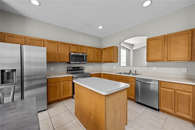 kitchen featuring light tile flooring, a center island, stainless steel appliances, and a textured ceiling