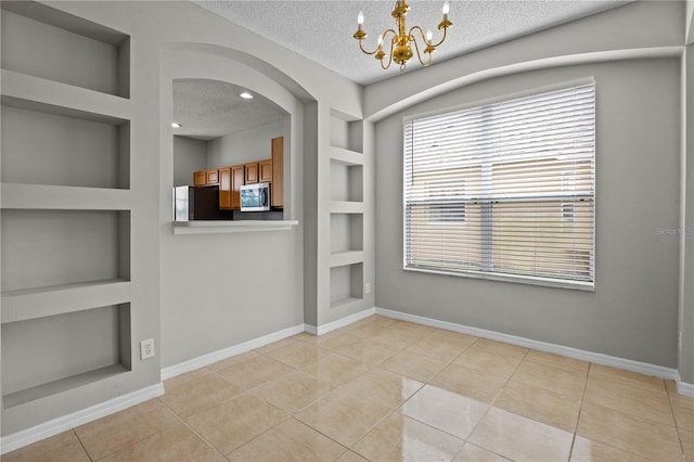 empty room with a textured ceiling, light tile floors, and built in features