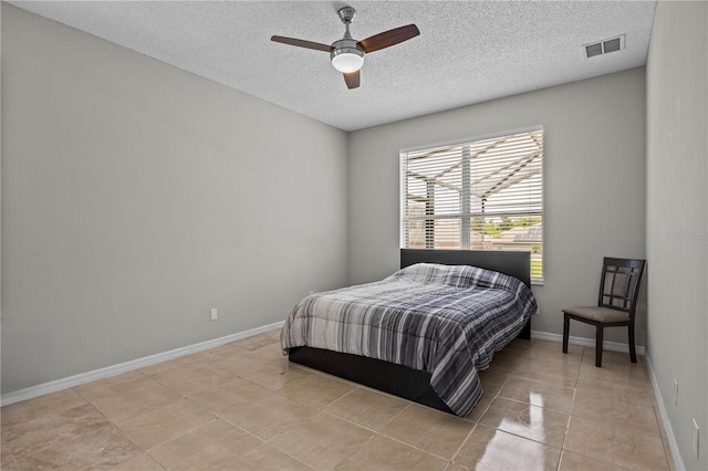 tiled bedroom featuring ceiling fan and a textured ceiling