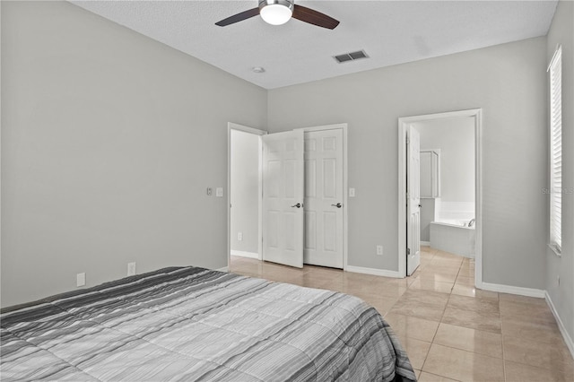 tiled bedroom featuring ceiling fan, ensuite bathroom, and a textured ceiling