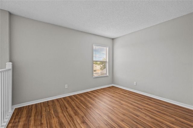 unfurnished room with dark wood-type flooring and a textured ceiling