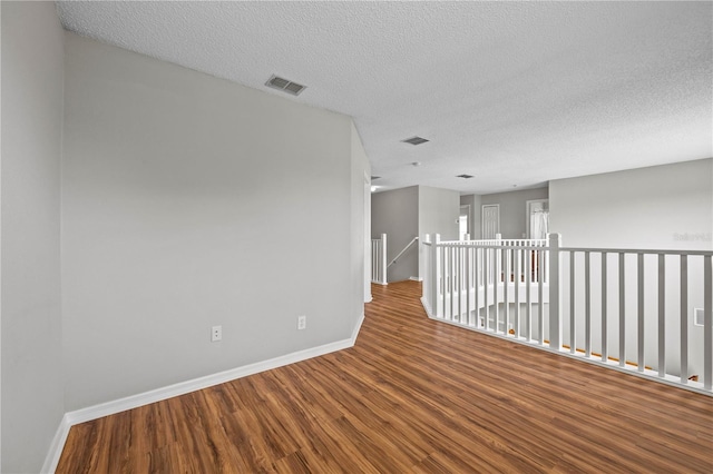 unfurnished room with hardwood / wood-style flooring and a textured ceiling