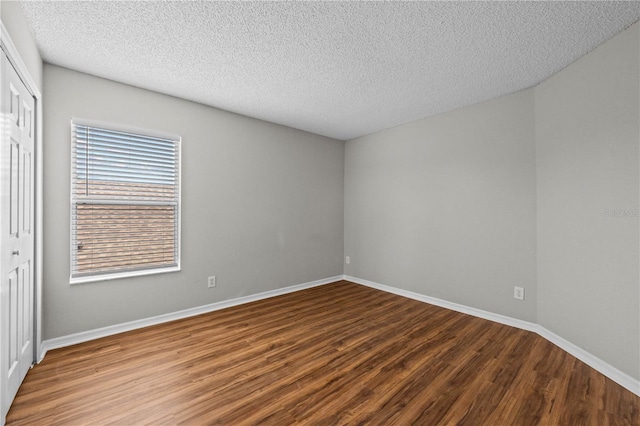 empty room featuring wood-type flooring, a healthy amount of sunlight, and a textured ceiling