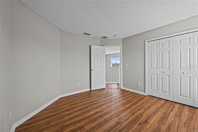 unfurnished bedroom featuring wood-type flooring, a closet, and a textured ceiling