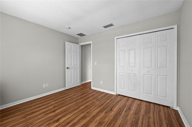 unfurnished bedroom with a textured ceiling, a closet, and dark wood-type flooring