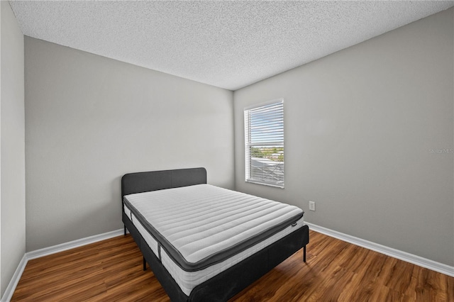 bedroom with dark hardwood / wood-style floors and a textured ceiling