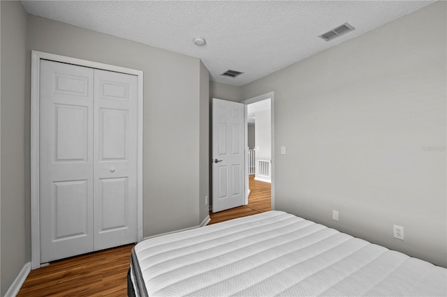 bedroom with a closet, hardwood / wood-style flooring, and a textured ceiling