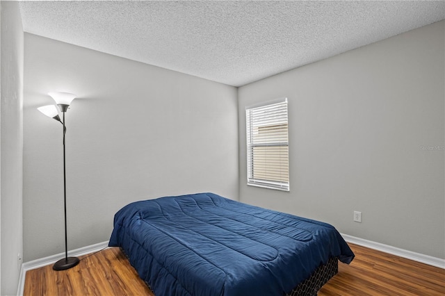 bedroom with a textured ceiling and dark wood-type flooring