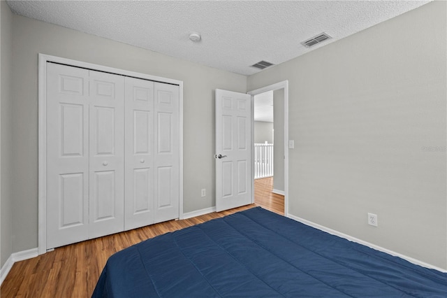 unfurnished bedroom with hardwood / wood-style floors, a closet, and a textured ceiling