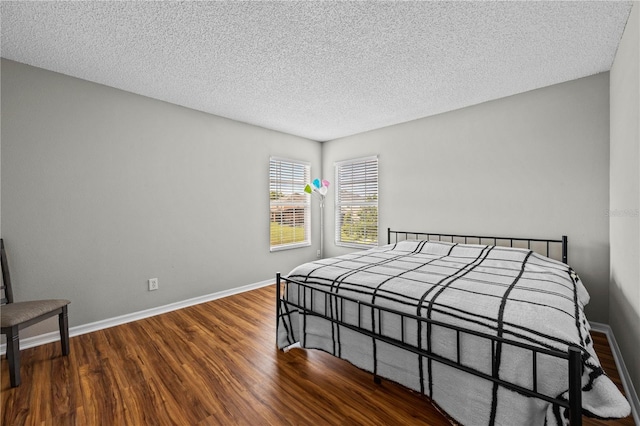 bedroom with dark hardwood / wood-style flooring and a textured ceiling