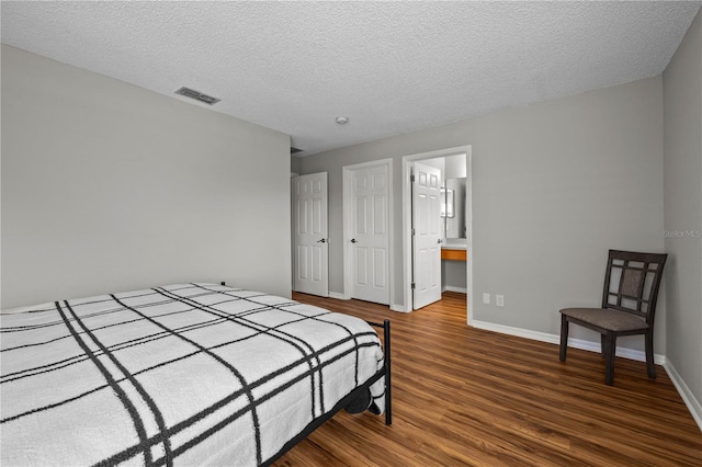 bedroom featuring connected bathroom, dark hardwood / wood-style floors, and a textured ceiling