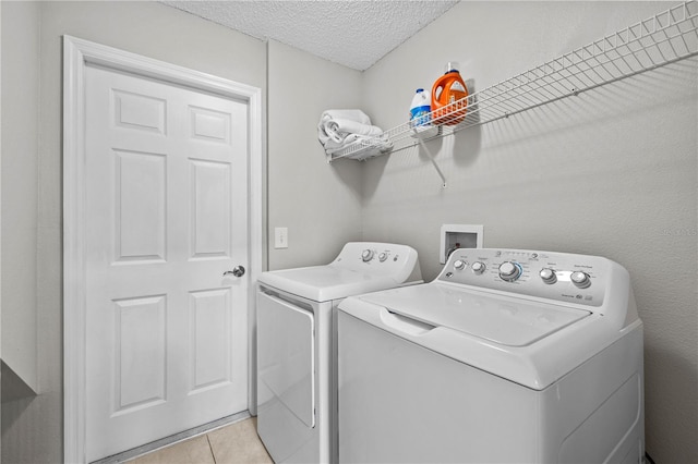 laundry area featuring a textured ceiling, separate washer and dryer, washer hookup, and light tile floors