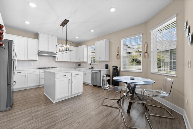 kitchen featuring white cabinets, plenty of natural light, stainless steel appliances, and a center island