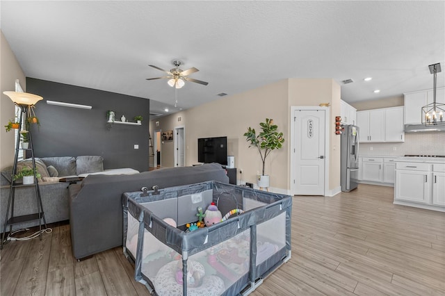 living room featuring ceiling fan with notable chandelier and light hardwood / wood-style flooring