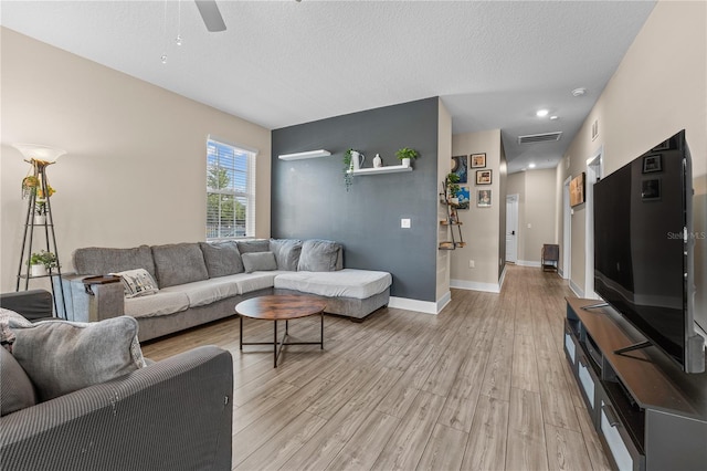 living room featuring a textured ceiling, ceiling fan, and light hardwood / wood-style floors