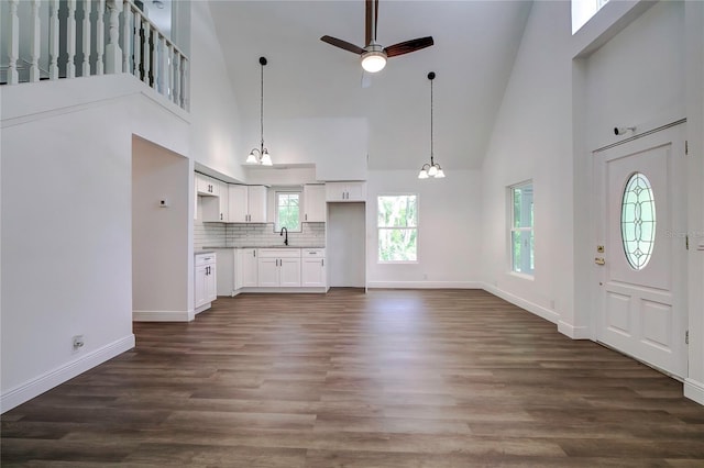 kitchen featuring white cabinets, decorative backsplash, and a towering ceiling