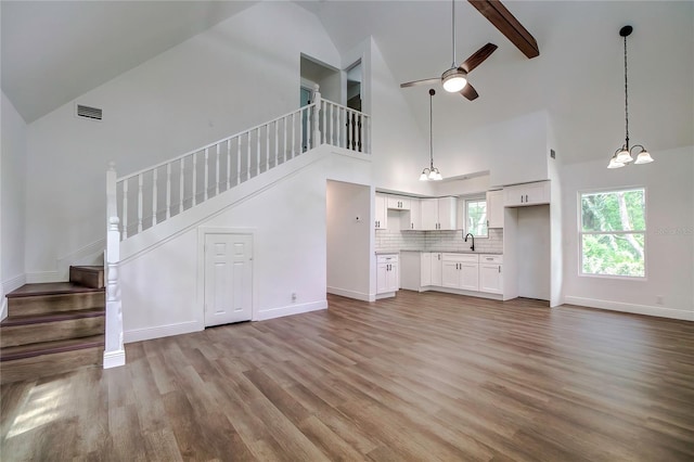 unfurnished living room featuring beamed ceiling, light hardwood / wood-style floors, sink, ceiling fan, and high vaulted ceiling