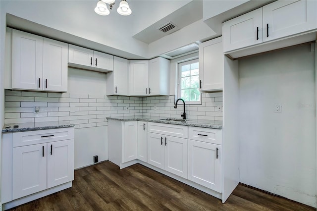 kitchen with white cabinets, light stone counters, and sink