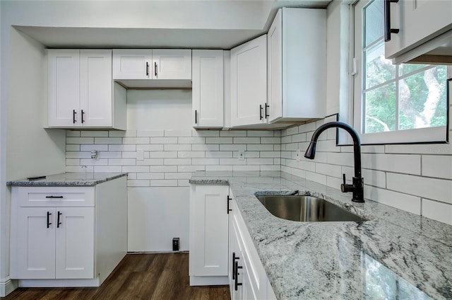 kitchen with light stone countertops, sink, backsplash, and white cabinets