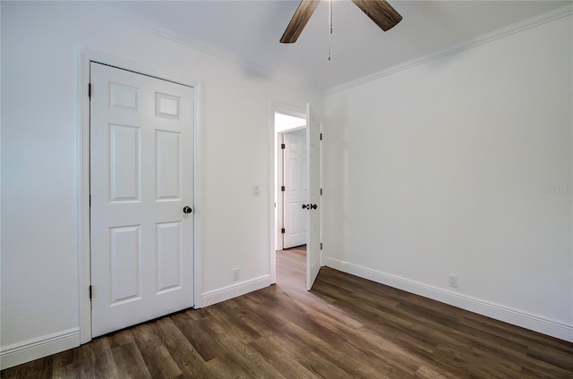 unfurnished bedroom featuring ceiling fan, a closet, dark hardwood / wood-style flooring, and crown molding