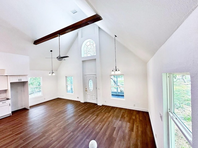 unfurnished living room featuring beamed ceiling, plenty of natural light, and dark hardwood / wood-style flooring