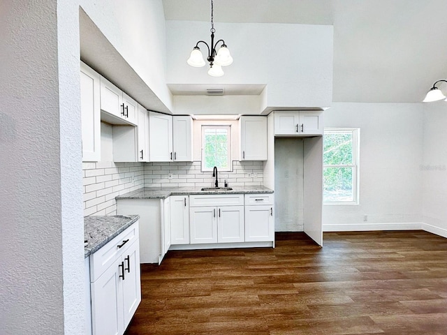 kitchen featuring light stone counters, sink, hanging light fixtures, and white cabinets