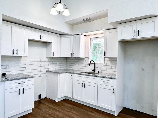 kitchen featuring sink, light stone countertops, white cabinets, and pendant lighting