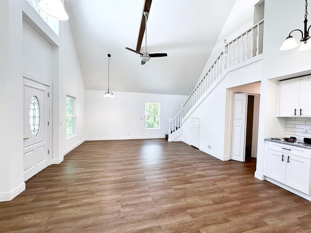 unfurnished living room featuring high vaulted ceiling, hardwood / wood-style floors, and ceiling fan with notable chandelier