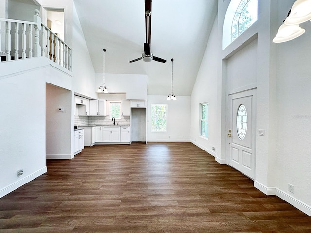 interior space with sink, dark wood-type flooring, ceiling fan with notable chandelier, and high vaulted ceiling