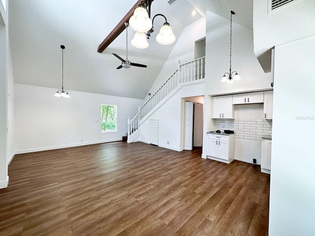 unfurnished living room featuring ceiling fan with notable chandelier, high vaulted ceiling, and dark hardwood / wood-style flooring