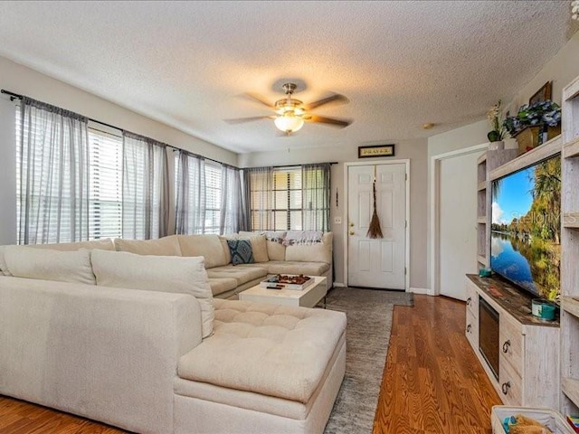 living room featuring ceiling fan, dark hardwood / wood-style floors, and a textured ceiling